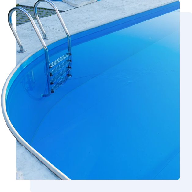 A partially curved, in-ground swimming pool with bright blue water and a metal ladder, bordered by a gray stone deck.